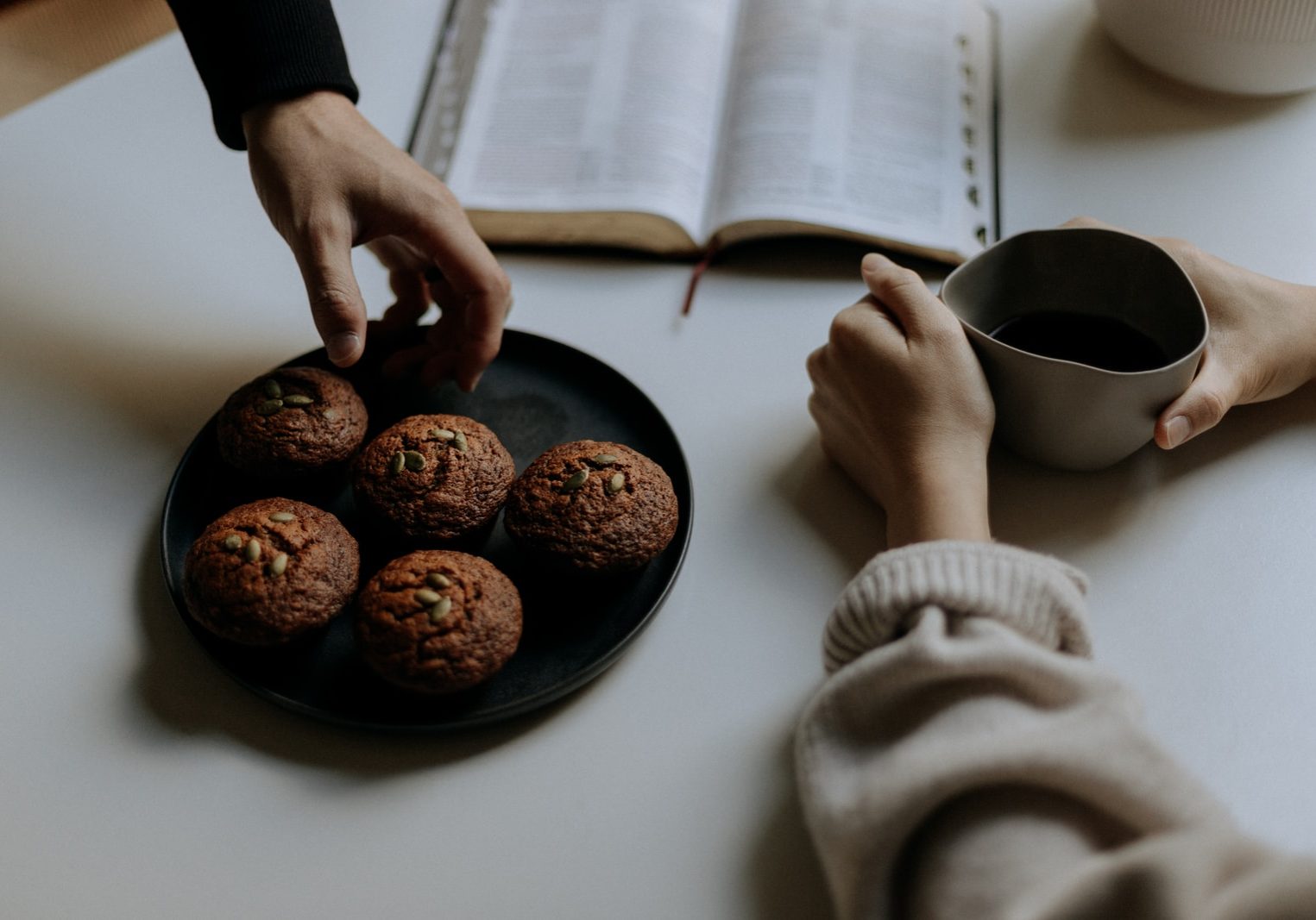 person holding black ceramic mug with coffee beans
