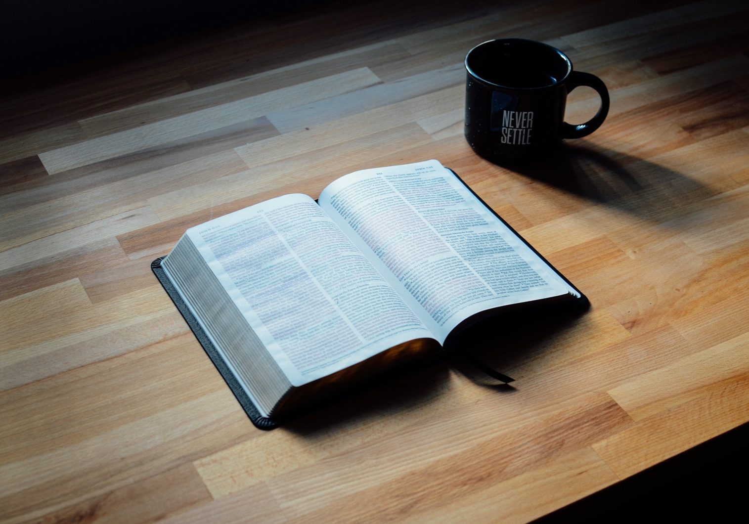 opened book beside black ceramic mug
